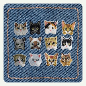 May include: A square patch of blue denim fabric with orange stitching around the border, featuring twelve embroidered cat head patches in various colors and patterns, including tabby, calico, Siamese, black, white, and gray feline designs.