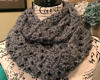 May include: Gray crocheted infinity scarf with a textured pattern. The scarf is displayed on a mannequin.