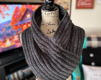 May include: A gray and black knit infinity scarf with a ribbed texture. The scarf is displayed on a mannequin with a vintage-style printed torso.
