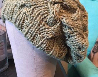 May include: A green knitted hat with a cable knit pattern. The hat is displayed on a mannequin head.