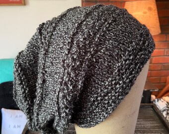 May include: A black and white slouchy beanie with a cable knit pattern.