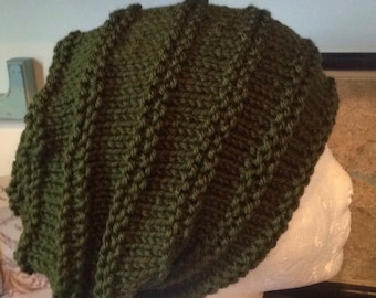 May include: A dark green knitted beanie with a textured, ribbed pattern. The beanie is displayed on a white styrofoam head.