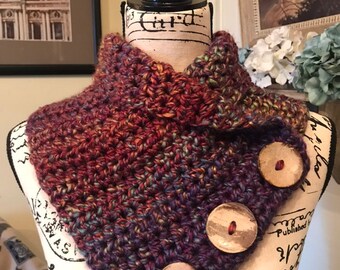 May include: A crocheted cowl in shades of purple, red, and brown with three wooden buttons.