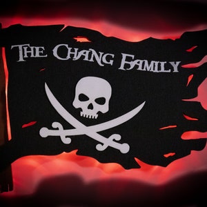 May include: Black pirate flag with a white skull and crossbones design, and the text "THE CHANG FAMILY". The flag has a tattered edge and is illuminated with a red glow.