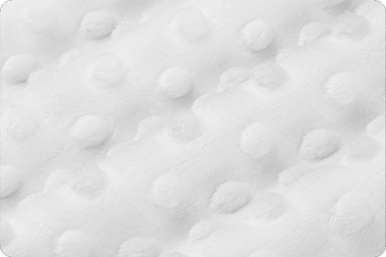 May include: Close-up of a white, textured fabric with a raised dot pattern. The soft material has a plush appearance, with a subtle sheen. The design creates a tactile, three-dimensional effect, suitable for various textile applications.