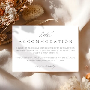 May include: A white rectangular card with the words "hotel ACCOMMODATION" in black. The card also includes details about a hotel room block for a wedding. Dried flowers in shades of orange and cream surround the card.