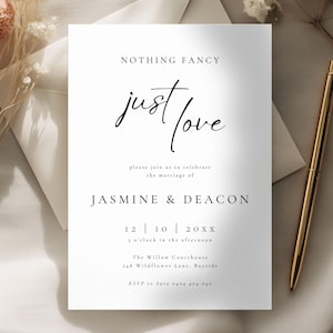 Puede incluir: Una invitación de boda blanca con las palabras "NOTHING FANCY" y "just love" en una fuente elegante. La invitación incluye los nombres Jasmine & Deacon, la fecha, la hora y los detalles del lugar. Un bolígrafo dorado y flores secas también están en la imagen.
