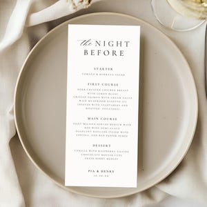 May include: A wedding menu card on a white plate with a knife and a glass of wine. The menu reads "The Night Before" and lists the courses: starter, first course, main course, and dessert. The menu is cream-colored with black text.