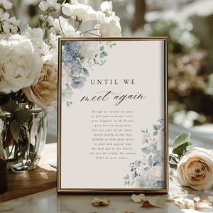May include: A framed sign with the text "UNTIL WE meet again" in elegant script. The sign is decorated with watercolor floral arrangements in shades of blue and white. The background is a soft beige.