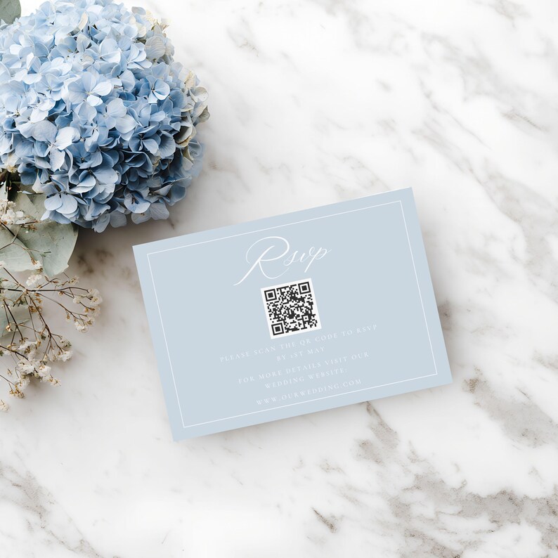 May include: A light blue RSVP card with white text and a QR code. The card is rectangular with a white border and is placed on a marble surface next to a blue hydrangea flower.