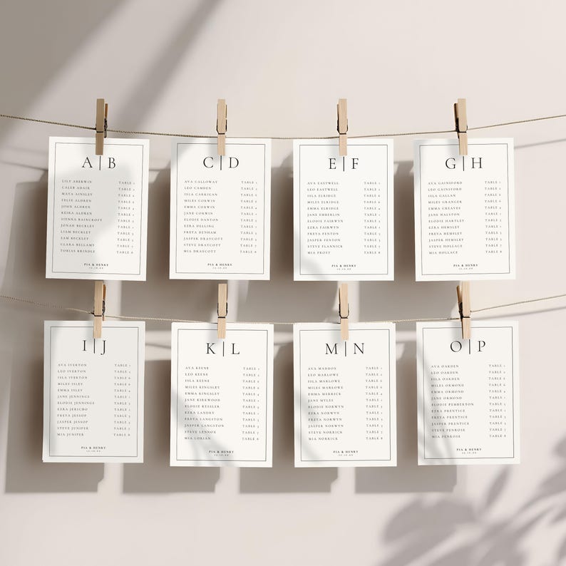 Op de afbeelding: Acht witte rechthoekige kaarten met zwarte tekst, vastgeklemd aan een touwtje met houten wasknijpers. Elke kaart heeft een letter en een lijst met namen, waarschijnlijk voor een bruiloftstoewijzing. De kaarten zijn in twee rijen van vier gerangschikt.
