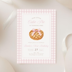 Puede incluir: Una tarjeta de invitación de cumpleaños rectangular con un borde de cuadros vichy en rosa claro y blanco. El centro muestra una ilustración en acuarela de un pastel dorado con un lazo rosa y el texto Our Little Cutie Pie.
