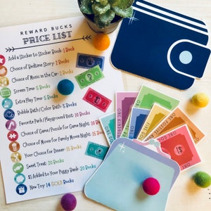 Puede incluir: Una cartera azul con una solapa blanca y un círculo blanco en la parte delantera. La cartera está abierta y contiene una variedad de billetes de papel de colores. Los billetes tienen las palabras "One Gold", "One Kindness", "One Positive", "One Good" y "One $1" impresas en ellos. La cartera está sobre una superficie de madera con algunas pequeñas bolas de colores esparcidas alrededor.