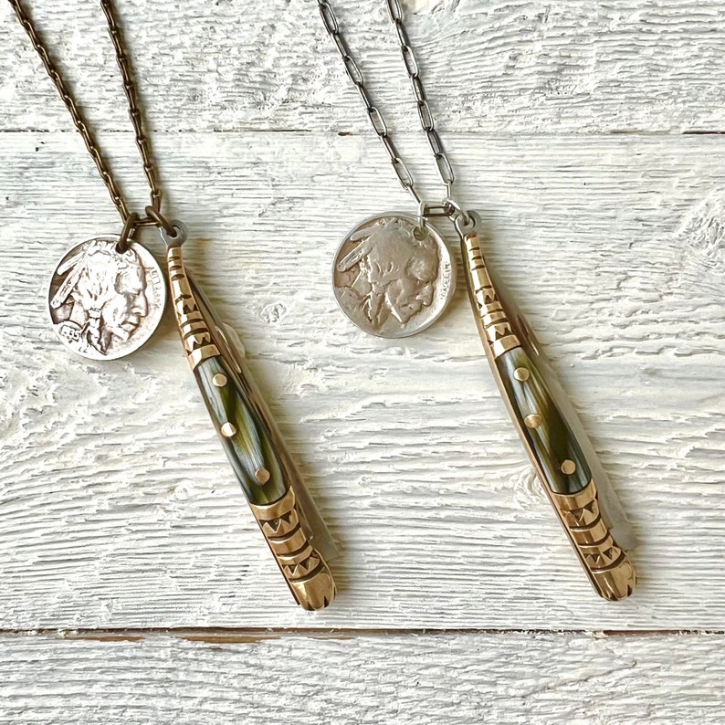 May include: Two gold necklaces with a silver chain and a brass chain. Each necklace has a silver Indian head nickel coin pendant and a small pocket knife pendant with a green and gold handle.