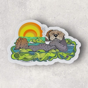 May include: A sticker featuring a cartoon otter floating in water, holding a cup of coffee, with a sunset in the background. The otter is surrounded by green seaweed and small islands. The sticker has a white border.