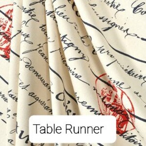 May include: A cream-colored table runner with a black and red print of handwritten text and a small red image. The text includes the words "The College" and "Demeuran".