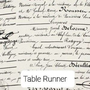 May include: A white table runner with a vintage French script design. The text includes the words "Table Runner" and "2020deguat".