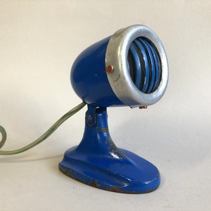 May include: A vintage blue microphone with a silver grille and a green cord. The microphone is on a blue stand with a rounded base.