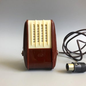 May include: A vintage brown and cream microphone with a black cord and a 3.5mm jack. The microphone has a grill on the front and a small label on the bottom.