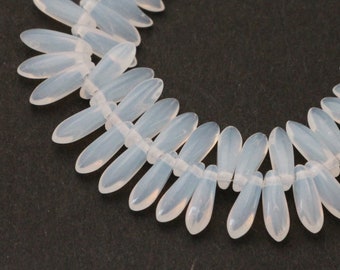 May include: Strand of opalescent, elongated oval beads. Each bead is approximately 1 inch long. The beads are strung together, creating a curved shape against a dark background. The beads have a soft, translucent appearance.