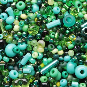 May include: A selection of green beads in various shapes and sizes. The beads vary in colour from pale yellow-green to deep emerald and teal. Some are round, others are cylindrical or ring-shaped, and some are transparent.