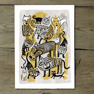 Peut inclure: Une illustration en noir et blanc d'un groupe de chats avec des accents jaunes et dorés. Les chats sont dans différentes poses, certains sont assis, certains sont debout et certains sautent. L'illustration est sur un fond gris clair.