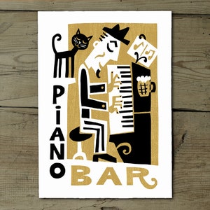 Peut inclure: Une illustration en noir et blanc d'une personne jouant du piano avec un chat assis sur le piano. Le texte "PIANO BAR" est écrit en lettres dorées sur un fond doré.
