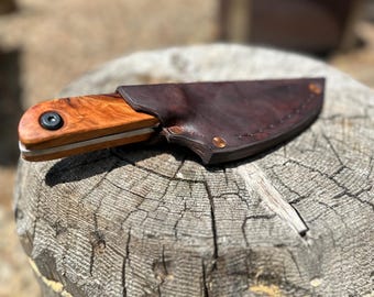 Cuchillo de supervivencia tradicional forjado a mano, modelo 5160, con acabado rústico, cachas extraíbles de cerezo nudoso y funda de cuero para diestros.