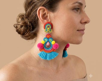 May include: Dangle earrings featuring a multi-colored soutache design with red, orange, yellow, and bright blue threads. The earrings include small pink pom-poms, a central pink teardrop bead, and a vibrant blue fringe at the bottom edge.