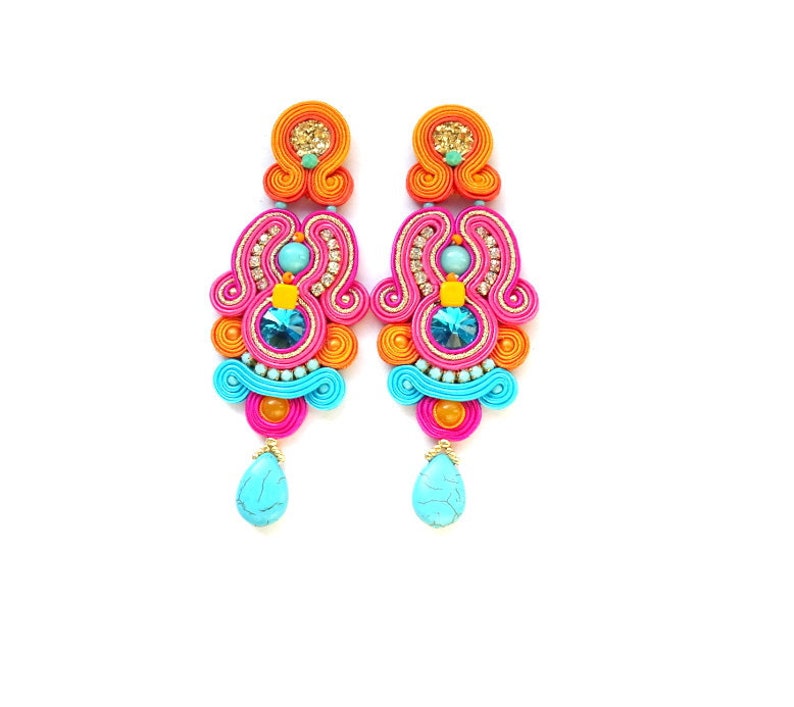 May include: A pair of colorful dangle earrings with turquoise, pink, orange, and gold accents. The earrings feature a teardrop-shaped turquoise stone at the bottom.