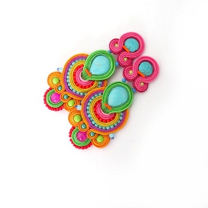 May include: A pair of colorful earrings with turquoise stones and a multi-colored design. The earrings are made with a variety of beads and threads.