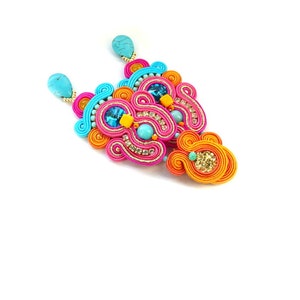 May include: A pair of colorful earrings with turquoise, orange, pink, and blue beads and rhinestones. The earrings are made of a woven cord material.