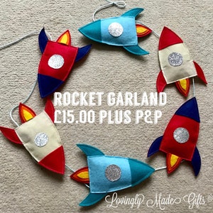 May include: A garland of felt rockets in blue, red, and beige with silver glitter accents. The garland is strung together with white thread. The text "ROCKET GARLAND £15.00 PLUS P&P" is visible in the image.