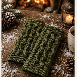 May include: A pair of olive green fingerless gloves featuring a vertical cable knit pattern with ribbed cuffs at both ends. The gloves are constructed from a thick yarn and display a consistent texture throughout the length of each piece.