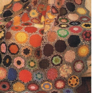 May include: A colorful crocheted blanket with a scalloped edge. The blanket is made up of many different colored squares, each with a different design. The blanket is folded in half and draped over a chair.