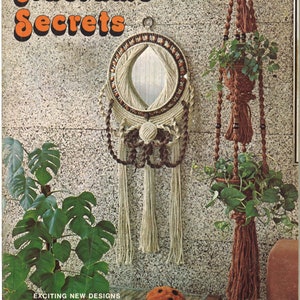 May include: A magazine cover featuring macrame designs. The cover features a macrame mirror, a macrame plant hanger, and a ladybug. The title of the magazine is "Macrame Secrets".