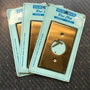 May include: Three packages of solid brass switch plates, labeled "Solid Brass Blue Chip Switch Plate" and "Solid Brass Blue Chip Switch". The plates are made in Taiwan for Heper Enterprises.