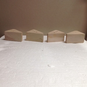 May include: Four unfinished wooden triangular blocks with rounded edges and holes drilled into the top surface.