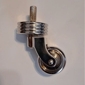 May include: A chrome swivel caster with a threaded stem and a grooved wheel. The caster is designed for furniture or other heavy objects.