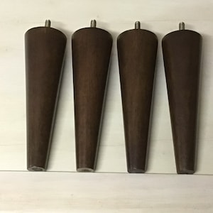 May include: Four brown wooden furniture legs with a tapered design and a silver screw at the top.