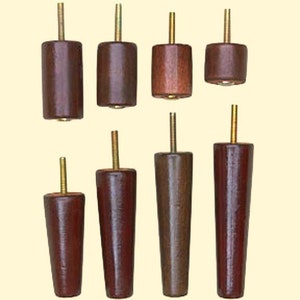 May include: Eight wooden furniture legs with a dark brown finish and gold metal threaded inserts. The legs are of varying lengths and diameters.