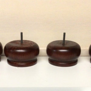 May include: Four dark brown wooden furniture legs with a metal screw in the center of each leg.
