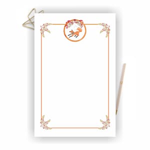 May include: Printable stationery featuring a fox with a red ribbon around its neck, surrounded by a wreath of leaves and berries. The stationery has a brown border and a white background.