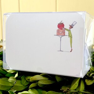 May include: A white card with a cartoon illustration of a person in a green suit and a top hat placing a red tomato on top of a cake on a table with a silver base.