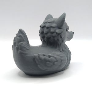 May include: A gray rubber duck with a wolf head and a textured, furry body.