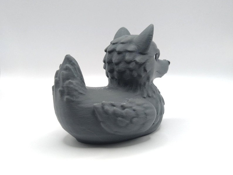 May include: A gray rubber duck with a wolf head and a textured, furry body.