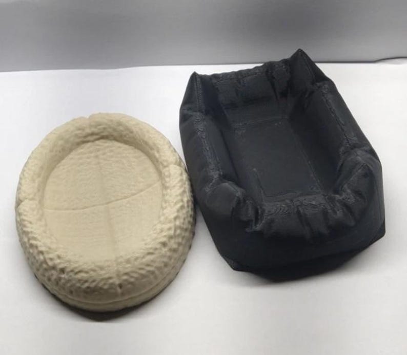 Op de afbeelding: Twee kleine, ronde, getextureerde bedden voor kleine huisdieren. Een bed is beige en de andere is zwart.