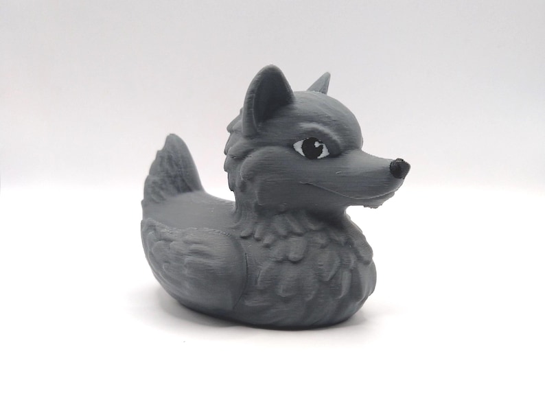 May include: A gray rubber duck with a wolf head and black eyes. The duck has a textured surface and is designed to float in water.