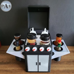 Puede incluir: Un organizador de condimentos y especias con tem&aacute;tica de barbacoa en blanco y negro. El organizador tiene una tapa con bisagras, perillas y un dise&ntilde;o de puerta de armario. Contiene frascos de especias, botellas y botellas exprimibles. El texto "BATON ROUGE" es visible.