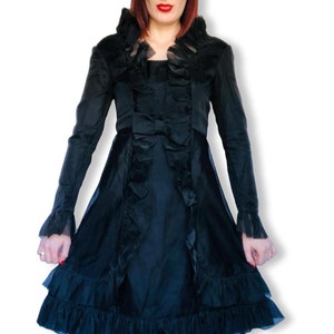 May include: A black dress with a ruffled collar and sleeves. The dress has a bow at the waist and a layered skirt with ruffles.